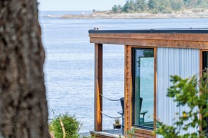 A wooden cabin with a large window overlooking a body of water. - UNIQUE RESIDENTIAL OCEANFRONT PROPERTY ON VANCOUVER ISLAND (Nanoose Bay)