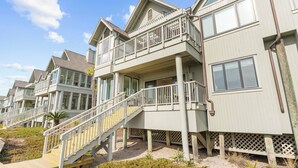 A beachfront property with multiple balconies, a staircase leading to the entrance, and a sandy beach area. - Incredible, completely renovated oceanfront villa (Kiawah Island)