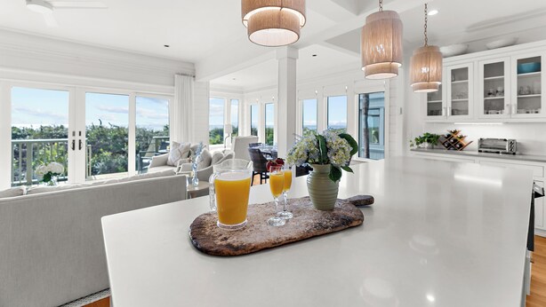A spacious kitchen with white cabinets, a large island, and pendant lighting. - Incredible, completely renovated oceanfront villa (Kiawah Island)