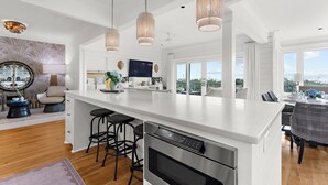 A modern kitchen with a large island, pendant lights, and a view to the outside. - Incredible, completely renovated oceanfront villa (Kiawah Island)