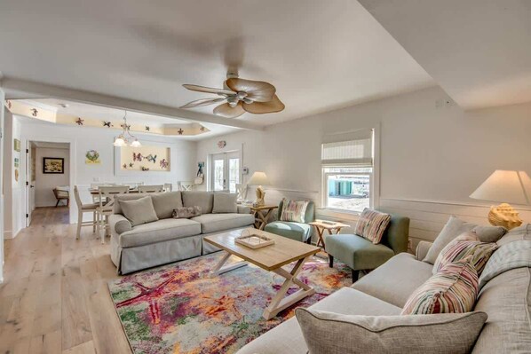 A spacious living room with a sectional sofa, a coffee table, and a ceiling fan.