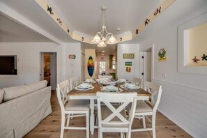 A dining area with a wooden table, white chairs, and a chandelier.