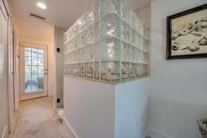 A hallway with a glass art installation, a door with blinds, and a framed picture on the wall.