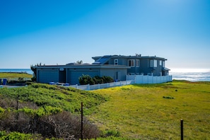 Una casa frente al mar con garaje, patio cercado y vista al océano.