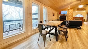 A wooden interior with a dining table, chairs, a fireplace, and a TV. - Beautiful mountain cabin (Sevierville)