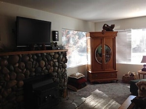 A living room with a stone fireplace, a television, a wooden cabinet, and a dog.