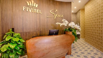 A reception area with a wooden reception desk, a computer, and potted plants.