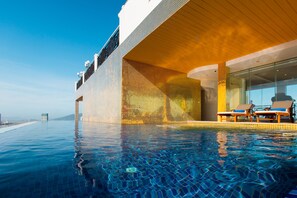A modern infinity pool with a clear view of the ocean, a covered seating area with lounge chairs, and a distinctive tiled wall design. - Fivitel Da Nang (Da Nang)