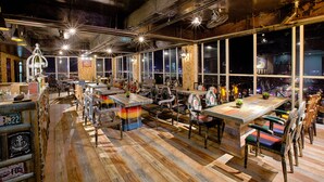 A spacious restaurant with high ceilings, exposed ductwork, and large windows offering city views. - Fivitel Da Nang (Da Nang)