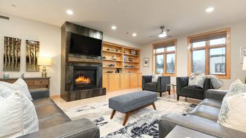 A living room with a fireplace, sofas, a coffee table, and a bookshelf.