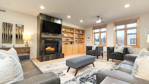 A living room with a fireplace, sofas, a coffee table, and a bookshelf. - LUXURY IN DOWNTOWN, A/C, GARAGE, SKI LOCKER ON MTN, FREE BUS,  2 KING 1 QN BED (Steamboat Springs)