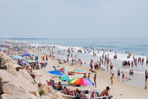 Een druk strand met veel parasols en mensen.