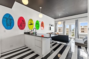 A modern kitchen with a central island, a dining area with a bench, and a view of the city through large windows.