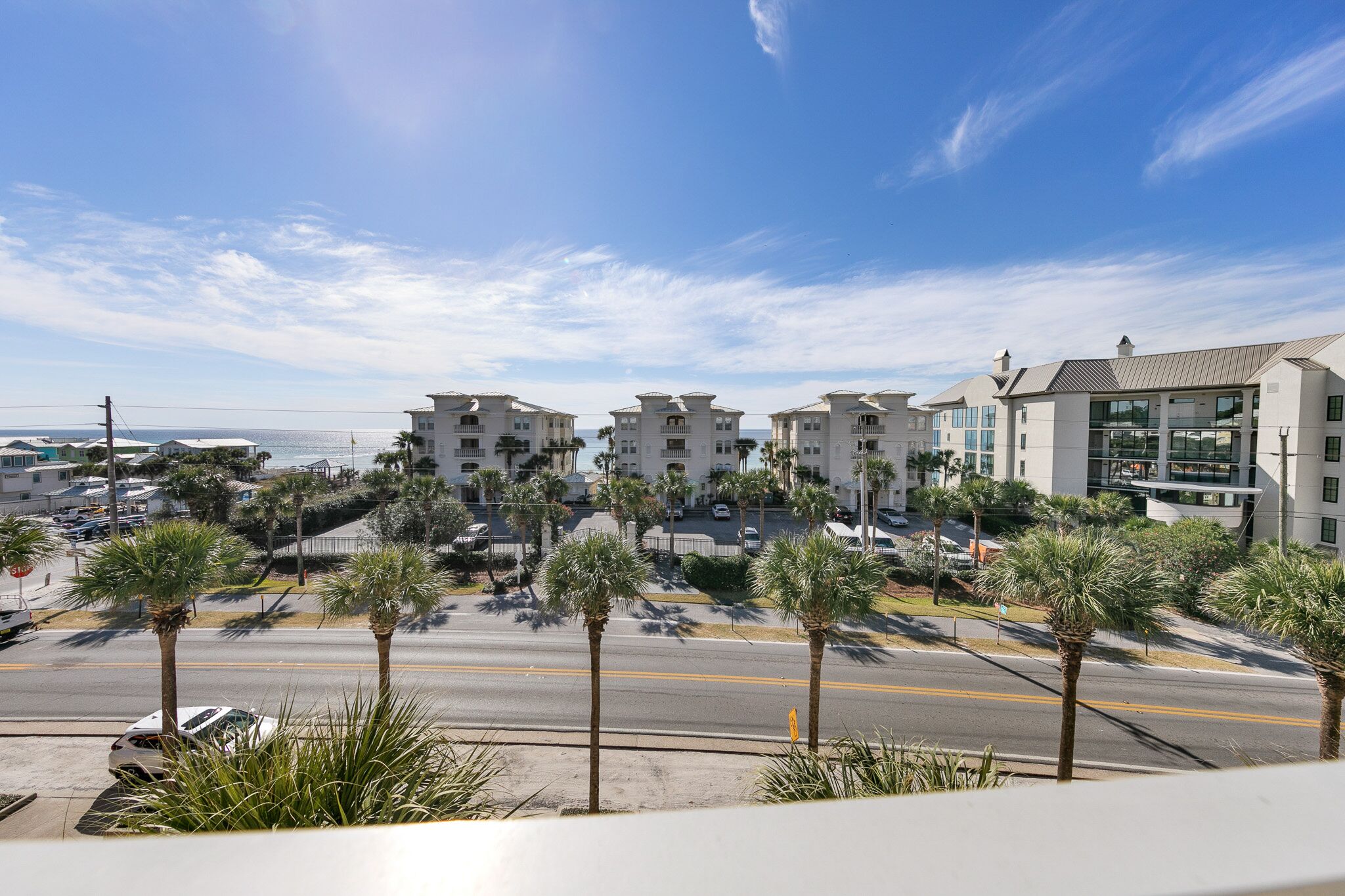 A coastal hotel with multiple buildings, palm trees, and a clear sky.
