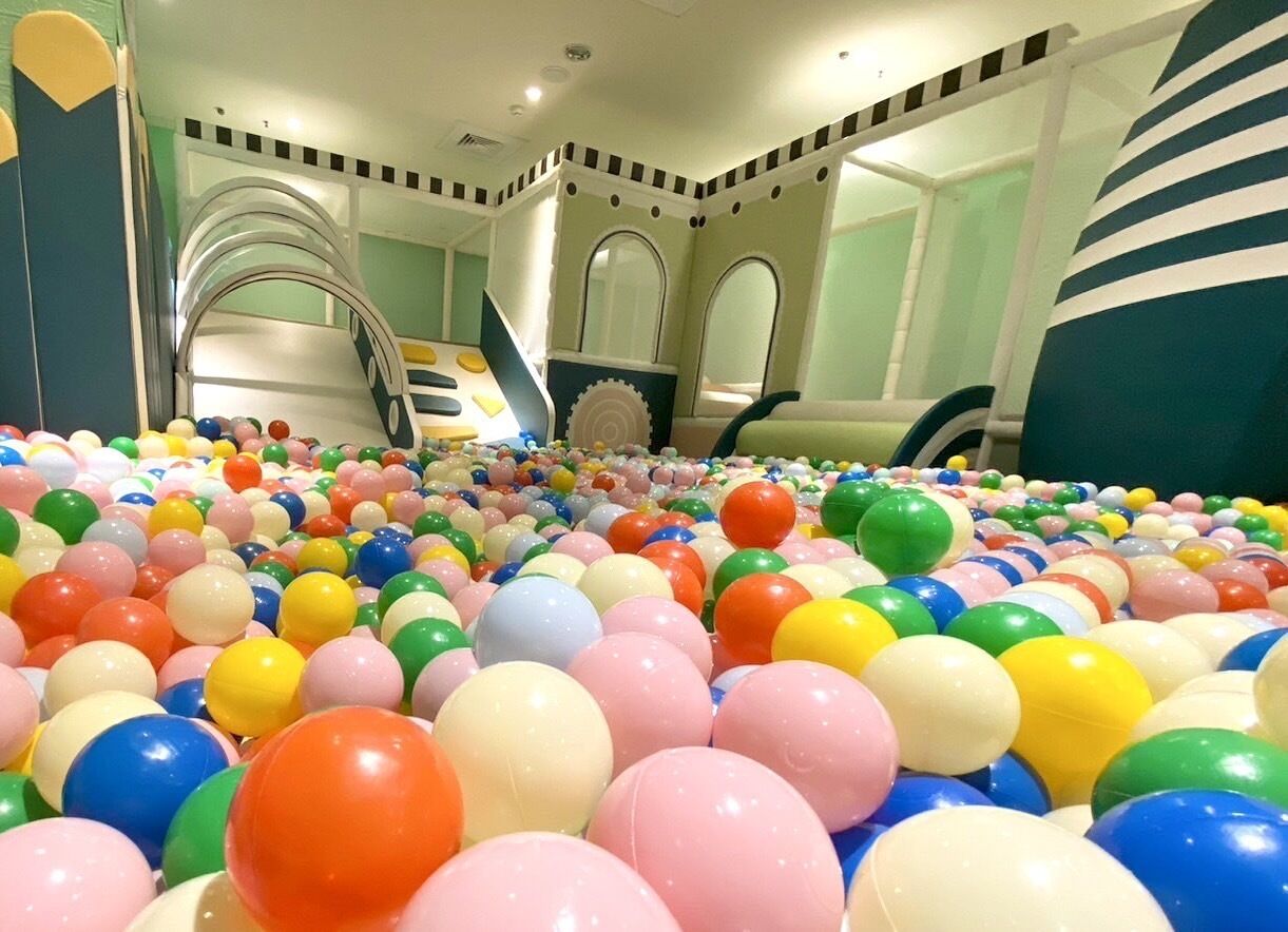 Un espacio de juego interior colorido con piscina de pelotas, toboganes y estructuras para escalar.