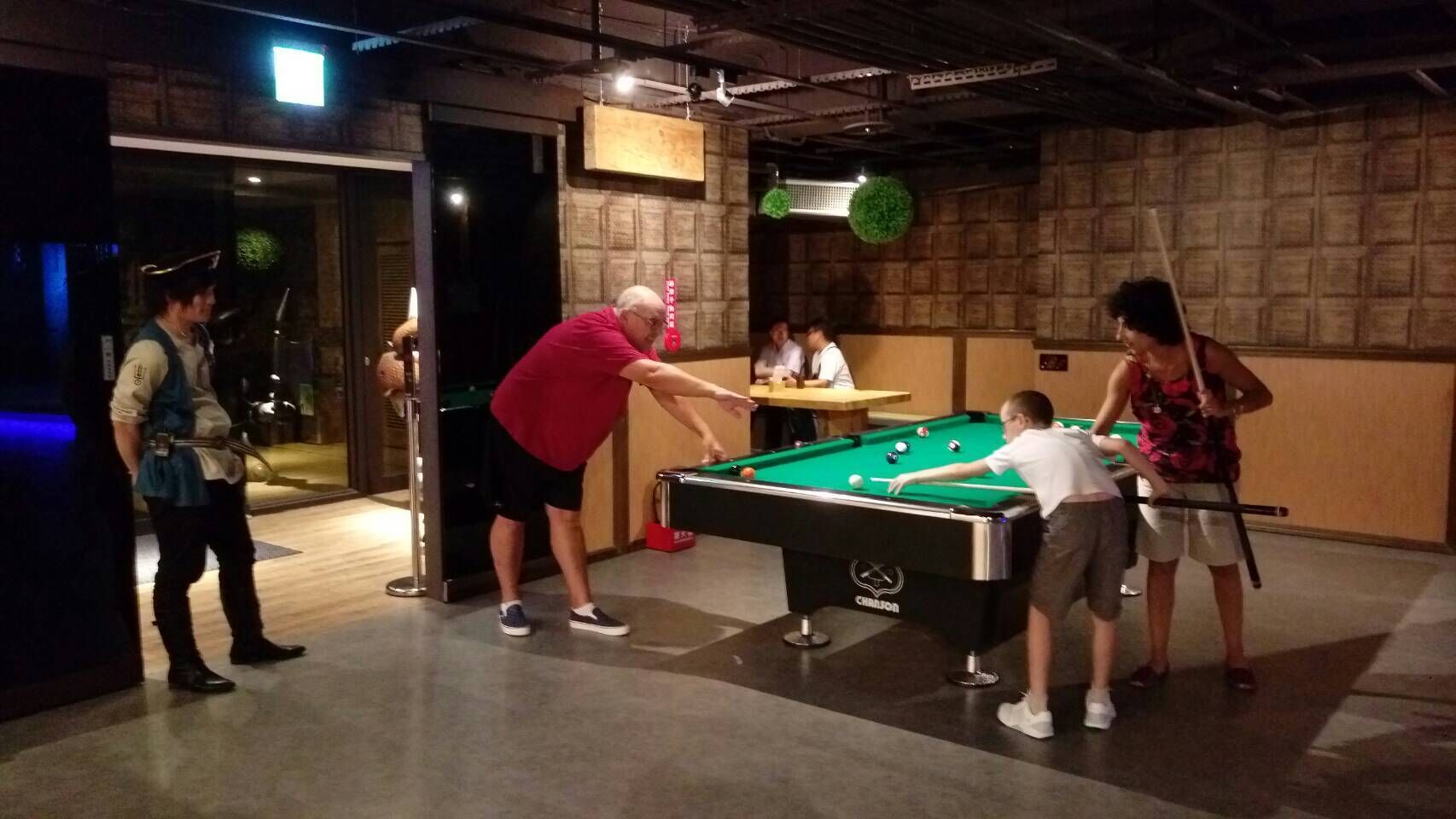 A pool table in a room with a brick wall and a ceiling fan.