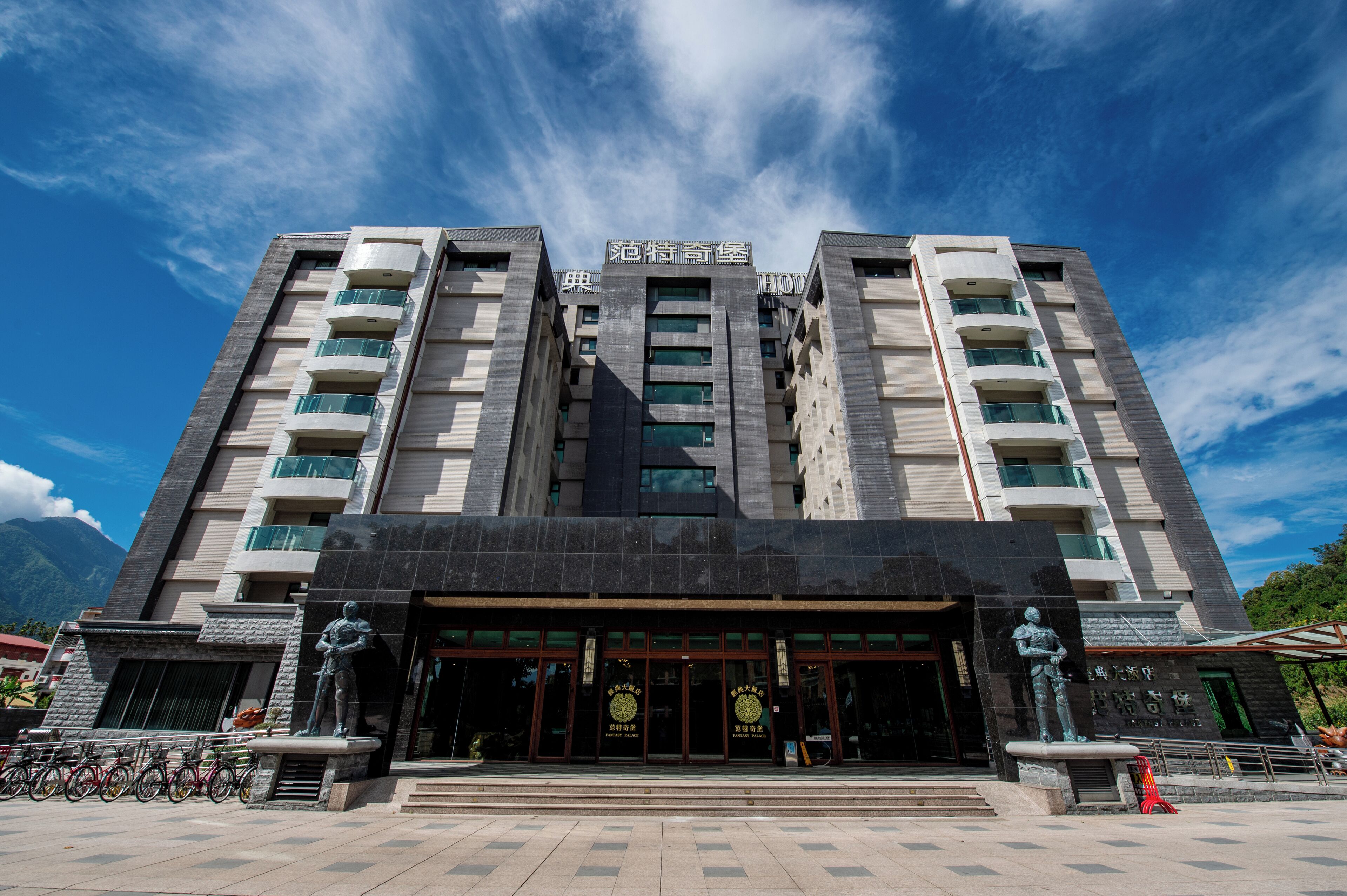 Un edificio moderno con una entrada destacada, varios balcones y un cielo despejado.
