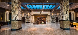 A spacious lobby with a high ceiling, stone pillars, and a central decorative sculpture. - Classic Hotel Fantastic Places (Yuchi)