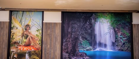 A conference room with a large screen displaying a waterfall and a fantasy-themed painting.