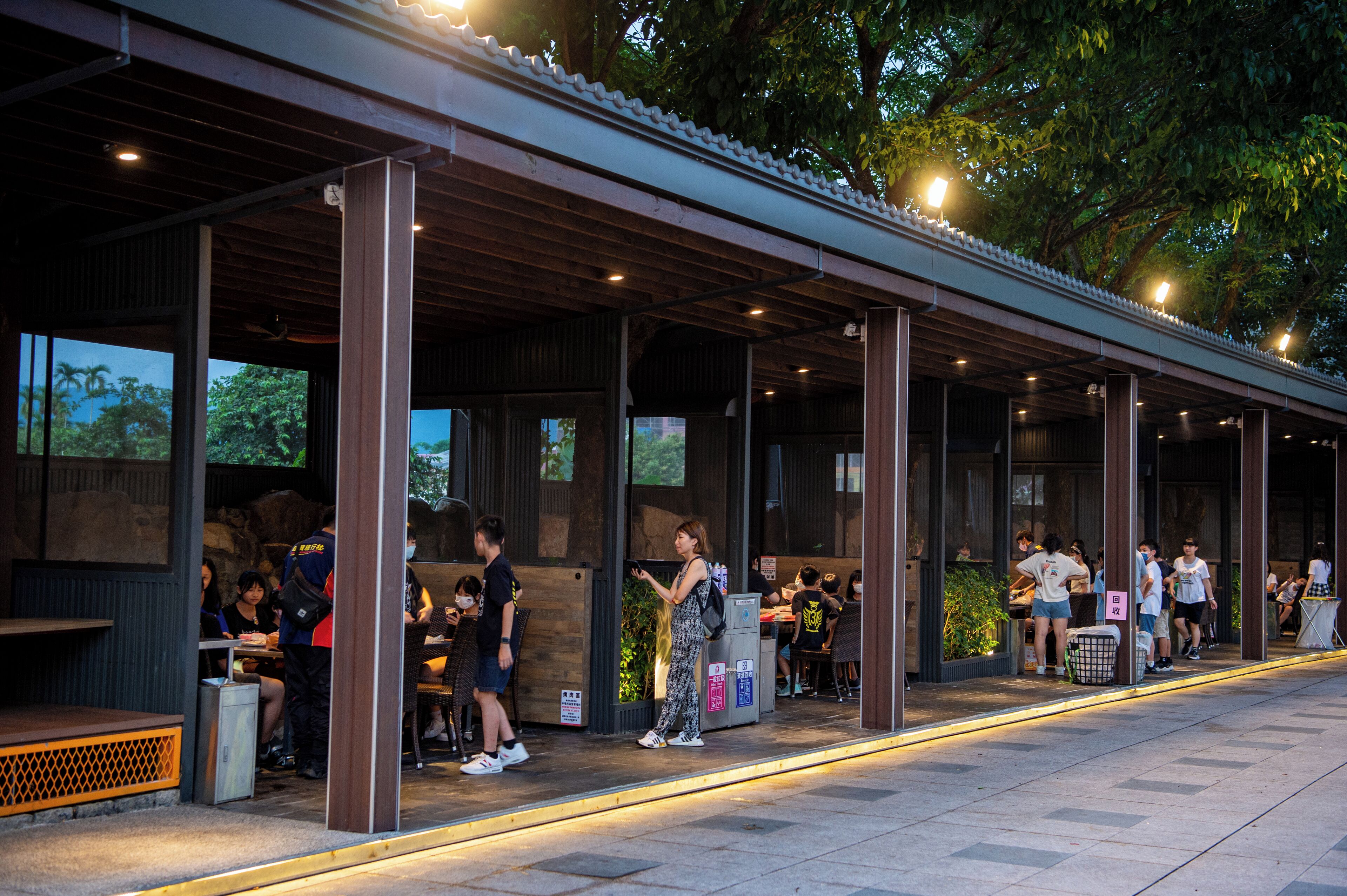 An outdoor restaurant with a covered seating area, wooden beams, and tables.