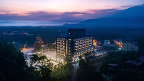 Et moderne hotel med en central gårdsplads, omgivet af bygninger og med et bjergrigt landskab i baggrunden.