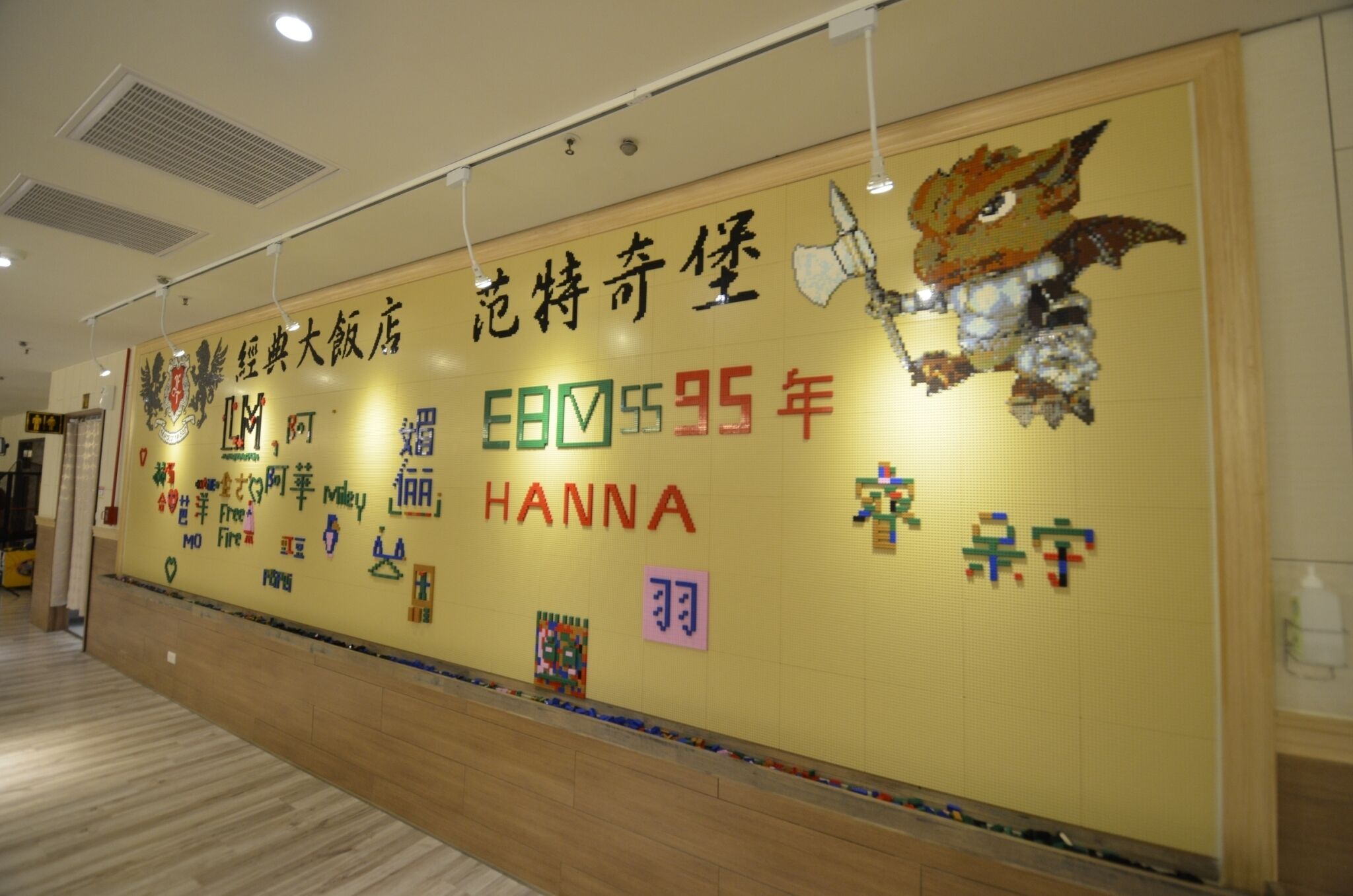 Una pared con diversas decoraciones, incluyendo un dinosaurio, un cartel con texto y símbolos coloridos.