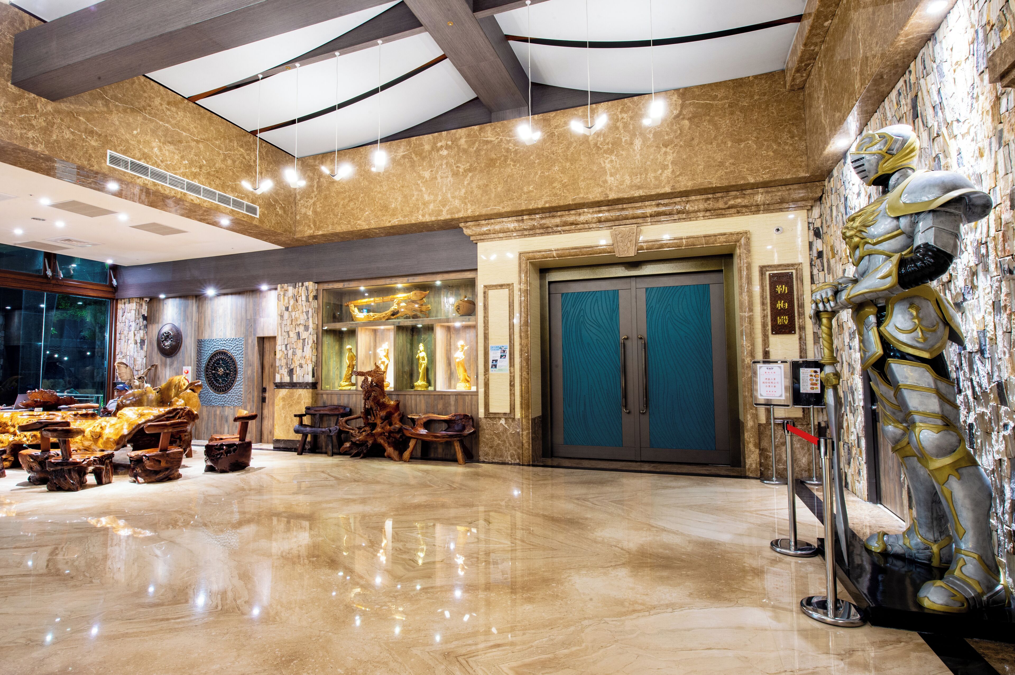 A spacious lobby with a polished marble floor, a large statue, and a reception desk.