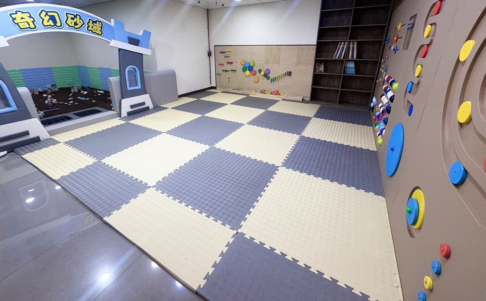 A play area with a checkered floor, climbing wall, and a playhouse.