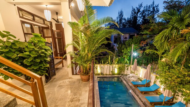 Uma área de piscina com espreguiçadeiras e plantas em vasos.