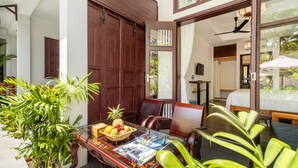 Quarto com porta de madeira, mesa de vidro com frutas e vista para o exterior.