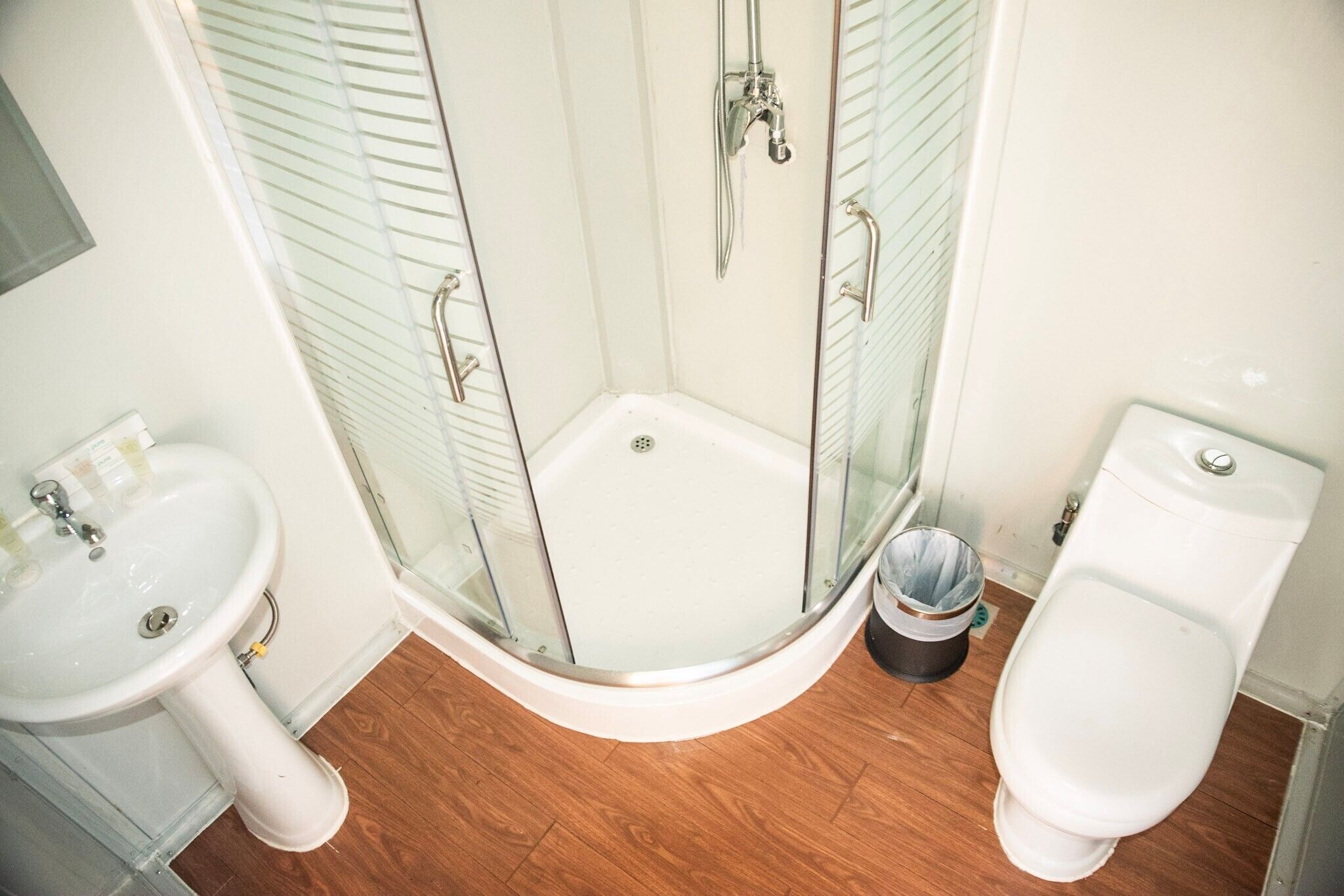A bathroom with a glass-enclosed shower, a sink, and a toilet.