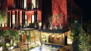 A modern building with multiple balconies, large windows, and a well-lit outdoor area with plants and a pool. - Golden Temple Villa (Siem Reap)
