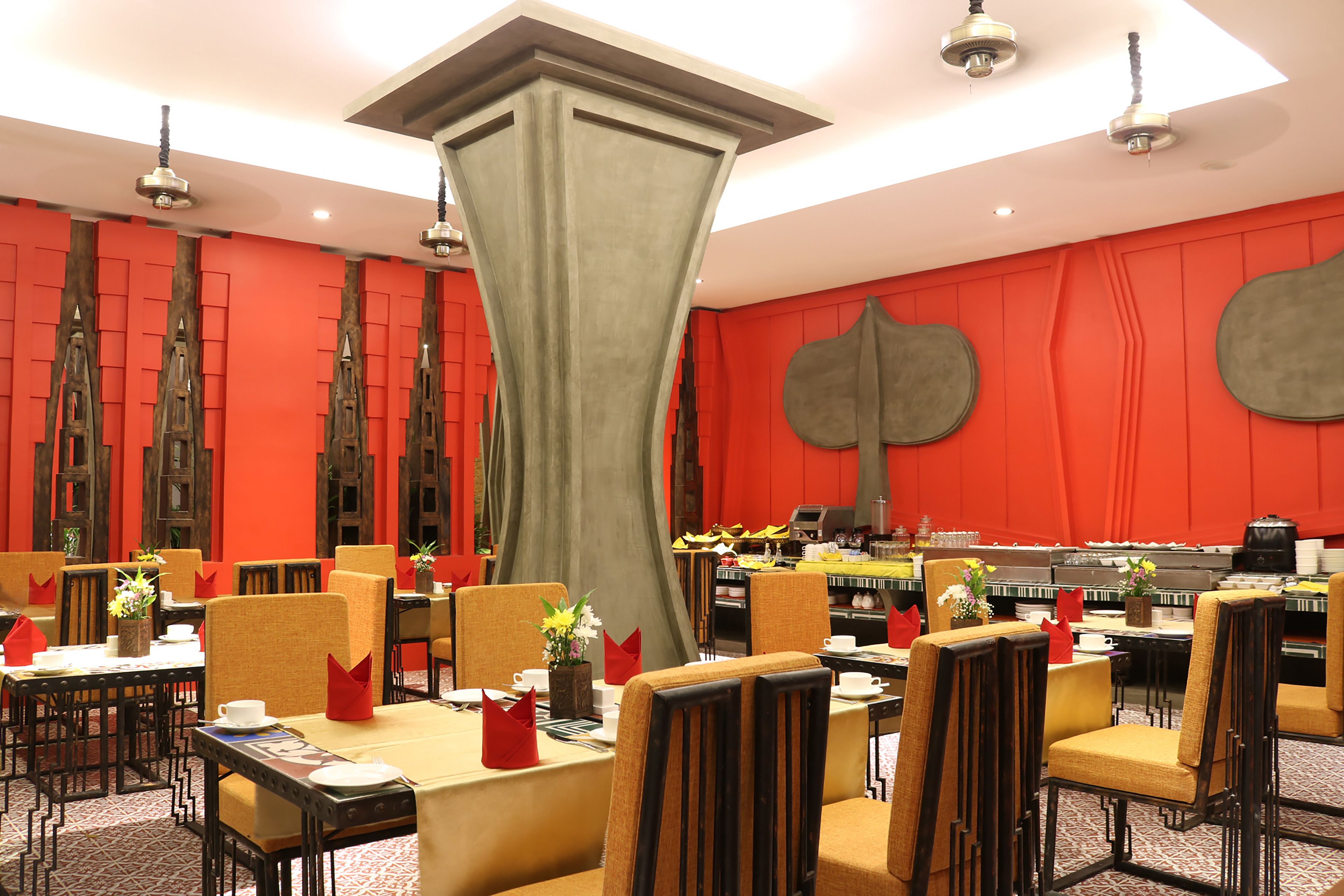 A dining area with tables set for service, chairs, and a central decorative column.