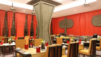 A dining area with tables set for service, chairs, and a central decorative column.