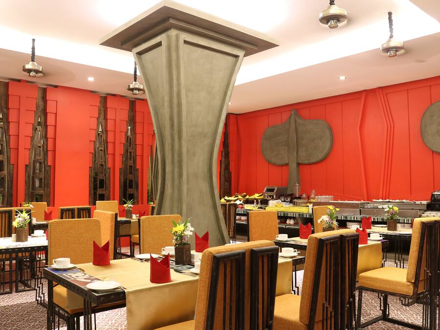 A dining area with tables set for service, chairs, and a central decorative column.