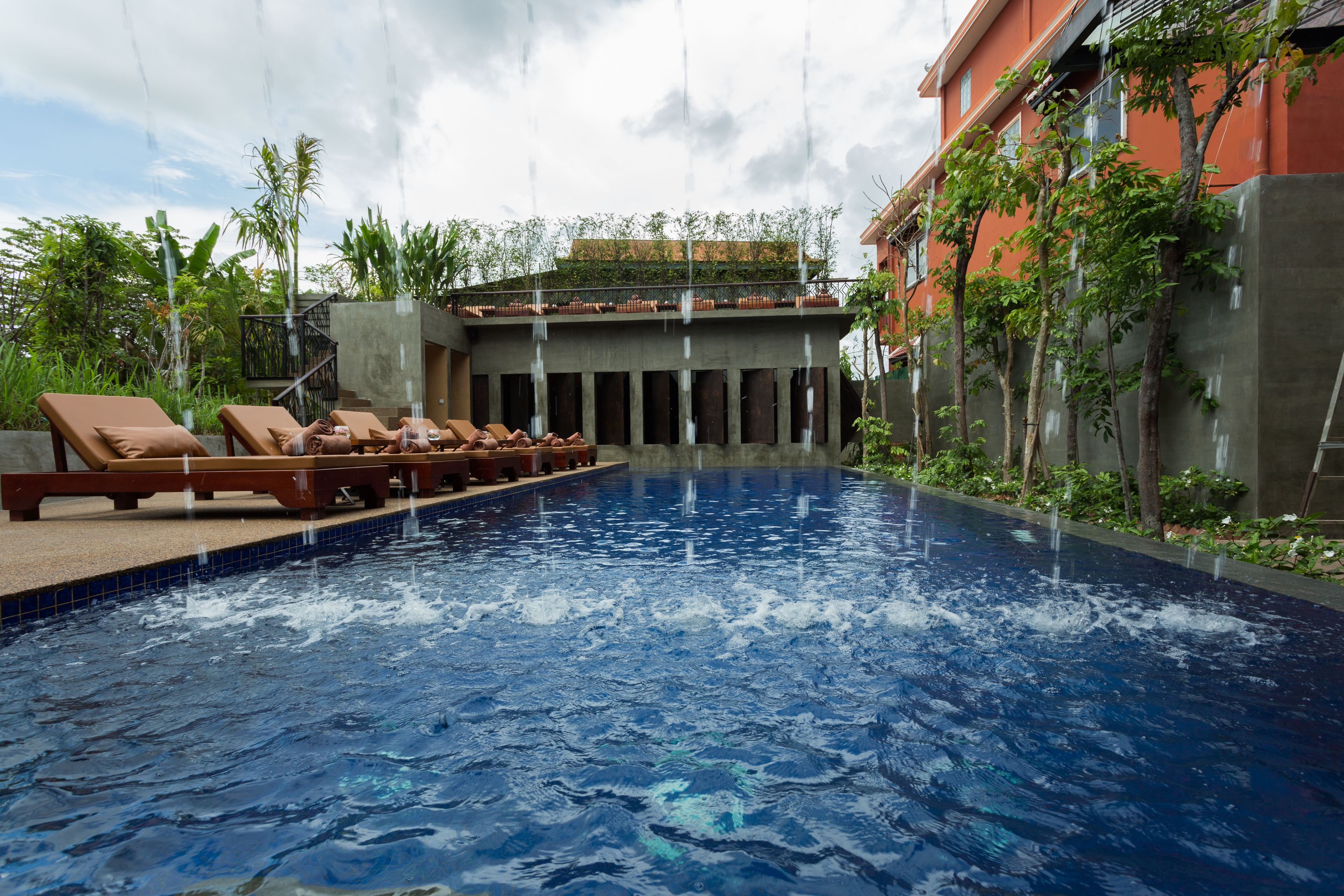 Una piscina con sillas de descanso y un edificio con techo verde.