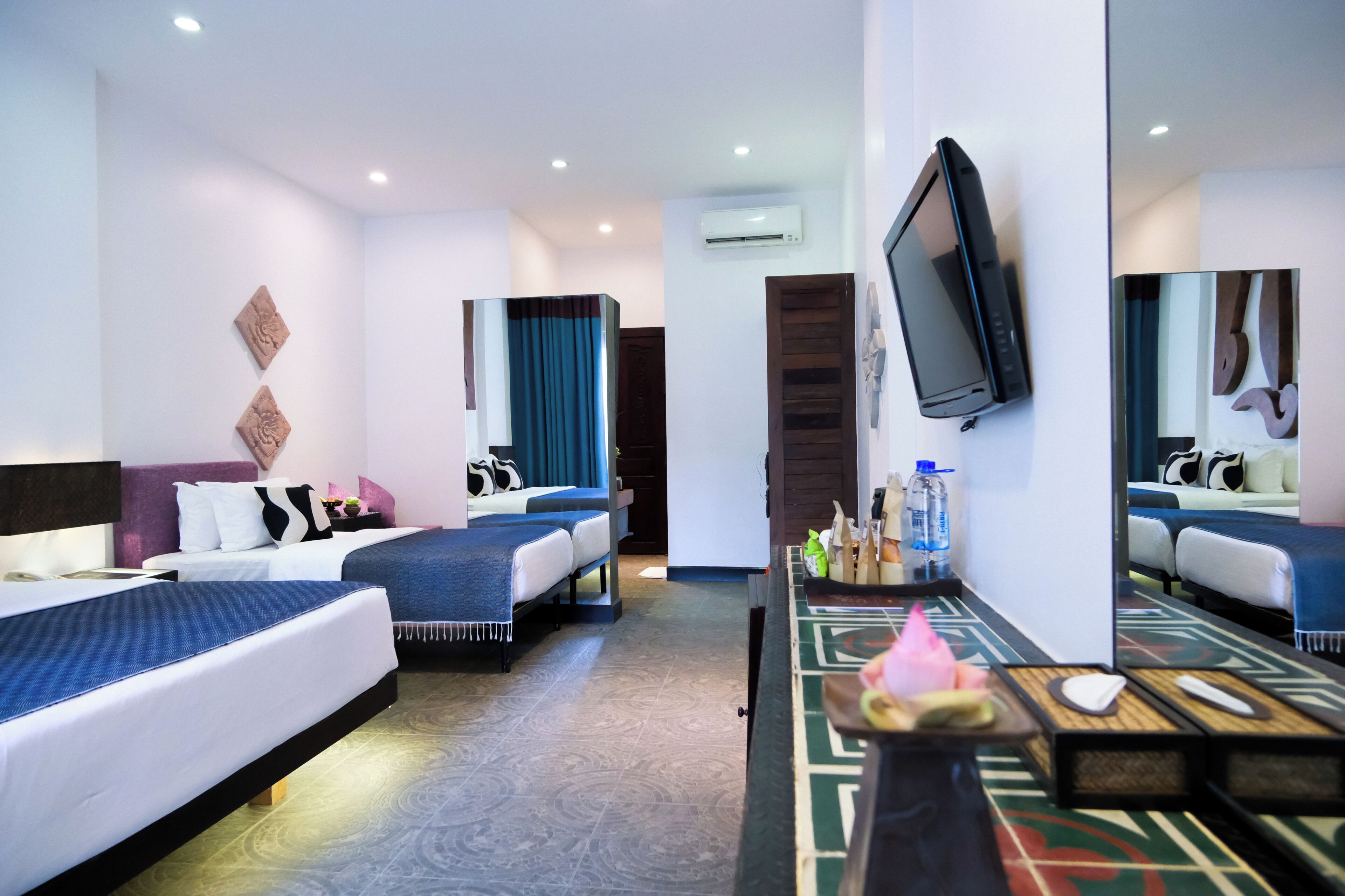 A hotel room with two beds, a TV, a mirror, and a small table with toiletries.