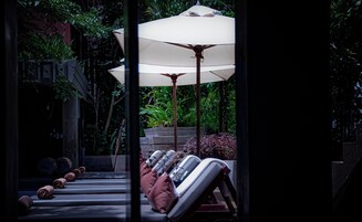 Una piscina al aire libre, sombrillas, sillones reclinables de piscina