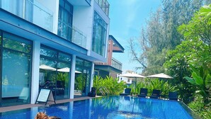 A woman sitting by a poolside with a wicker basket containing food and drinks. - Montgomerie Links Hotel & Villas (Da Nang)