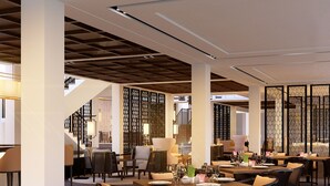A spacious restaurant with high ceilings and modern furnishings, featuring multiple dining tables and chairs. - Montgomerie Links Hotel & Villas (Da Nang)
