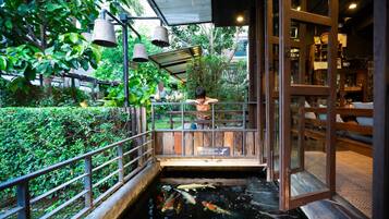 A koi pond with a wooden bridge and railing, surrounded by lush greenery.