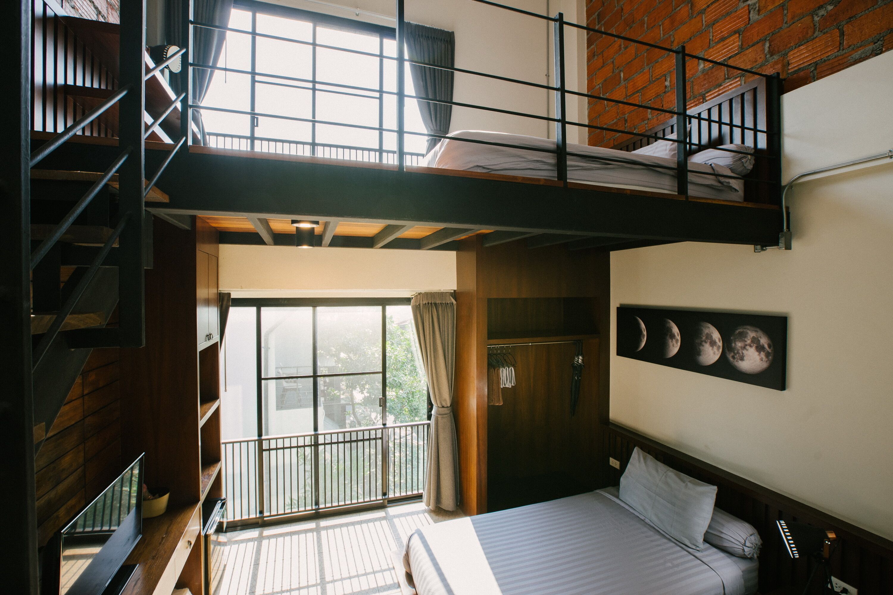 Quarto com cama beliche, varanda com vista e parede com calendário das fases da lua.