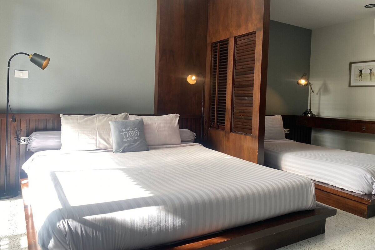 A modern bedroom with two beds, wooden headboards, and a large mirror.