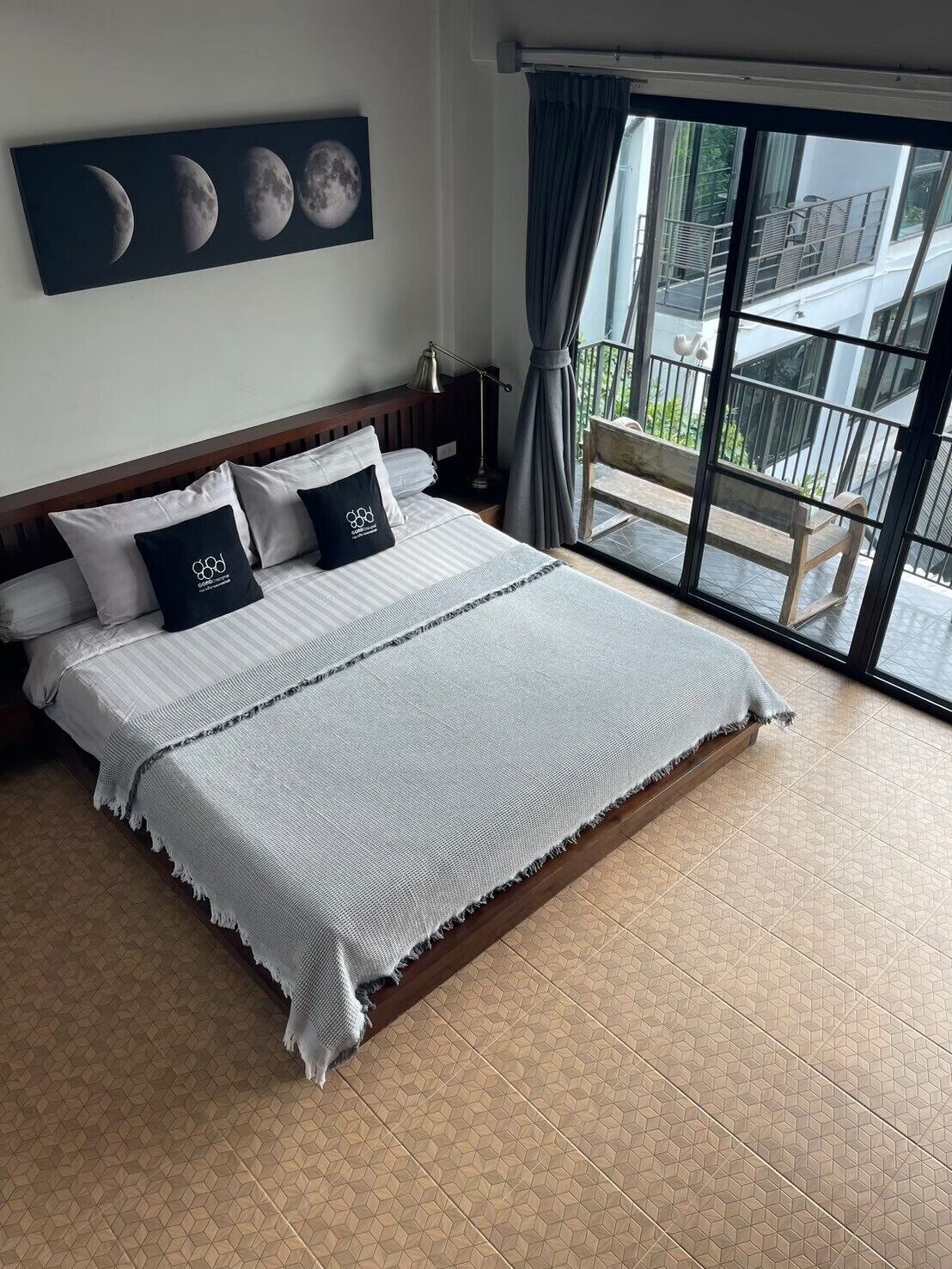 Una camera da letto con un letto grande, vista del balcone esterno e un muro decorato con immagini delle fasi lunari.