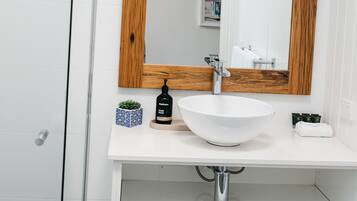 A bathroom with a white sink, wooden-framed mirror, and wicker baskets under the sink.