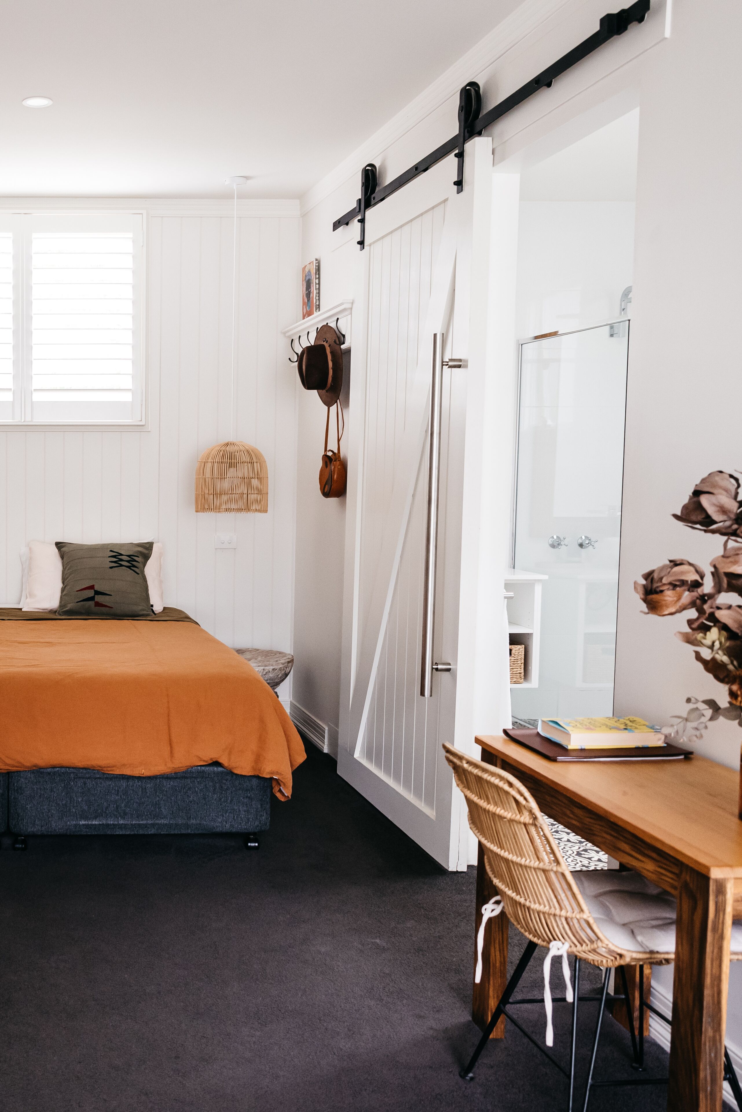 A bedroom with a bed, a wooden table, a chair, and a wardrobe with a sliding door.
