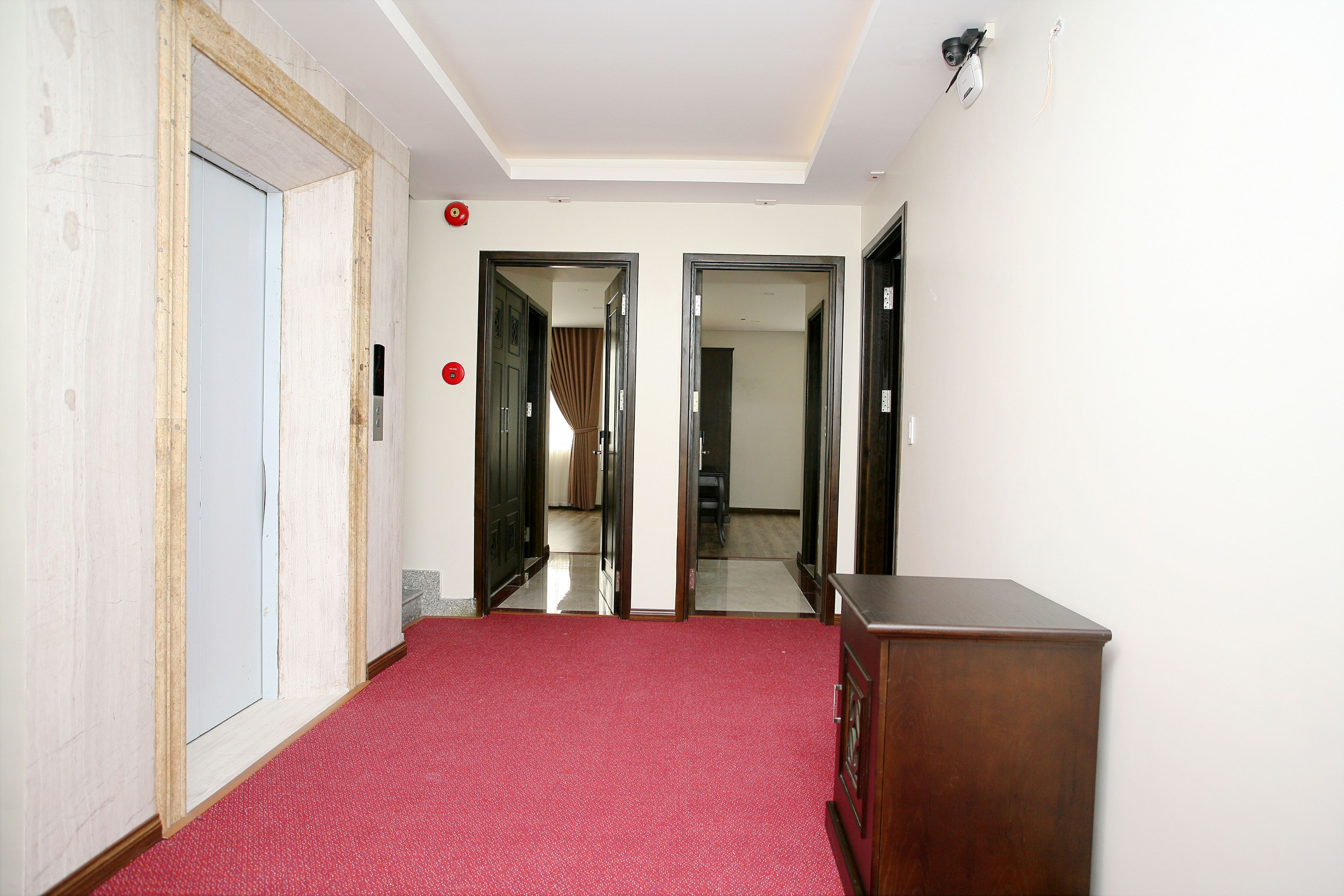 Un couloir avec un tapis rouge, des portes en bois et un meuble en bois.