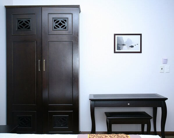 Una habitación con un armario de madera oscura, una mesita pequeña y un cuadro en la pared.