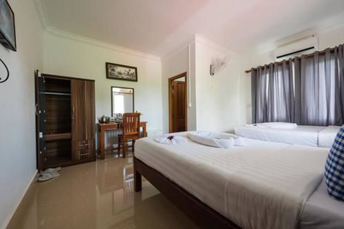 Ein Hotelzimmer mit Bett, Schreibtisch, Stuhl, Klimaanlage und Kleiderschrank.