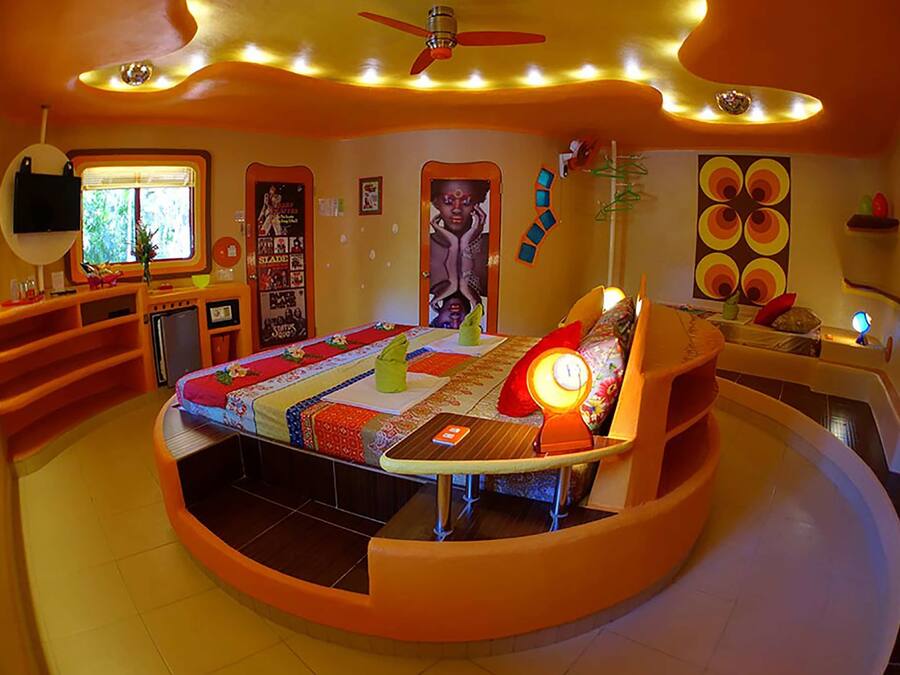 Una habitación circular con una cama, un escritorio y un ventilador de techo.